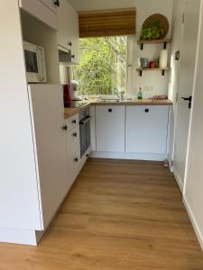 a kitchen with white cabinets and a wooden floor at Coquelicot in Waulsort +16 photos