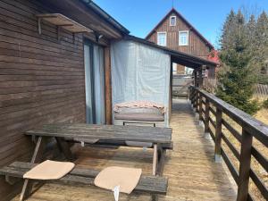 a wooden deck with a picnic table and two chairs at Bedřichov Jaroš in Bedřichov