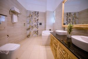 a bathroom with two sinks and a toilet and a tub at Emerald Bay Resort Mirissa in Mirissa