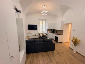 a living room with a black couch and a kitchen at Home Albert-Lago Maggiore Luino in Luino