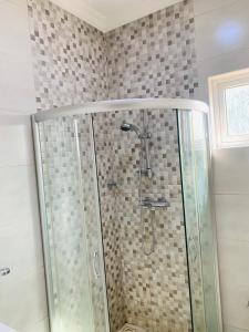 a shower with a glass door in a bathroom at Stylish and spacious room in a quiet environment in Dawhwenya +19 photos