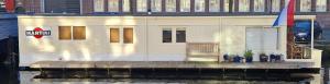 a white house with a dock in the water at Pantheos Top Houseboat in Amsterdam