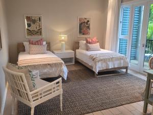 a bedroom with two beds and a chair and a window at Eden Island Gem in Eden Island +11 photos