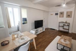 a living room with a table and a flat screen tv at Le Nid De Demolombe in Caen