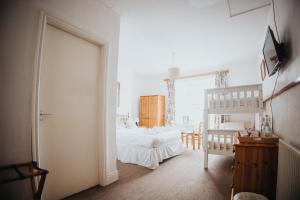 a white bedroom with a bed and a ladder at Y Pengwern in Ffestiniog