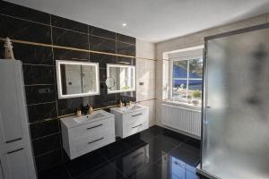 a black tiled bathroom with two sinks and a shower at Fleiš Residence villa - jacuzzi included in Most +8 photos