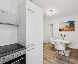 a kitchen with white cabinets and a table and chairs at Prime Host Balcony Apartment in Karlsruhe