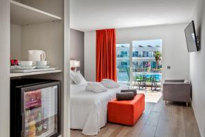1 dormitorio con 1 cama, 1 silla y TV en Barceló Corralejo Sands, en Corralejo
