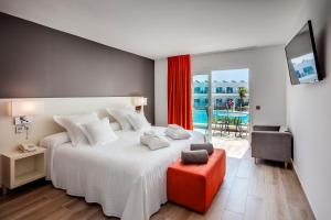 a bedroom with a large white bed and a red stool at Barceló Corralejo Sands in Corralejo