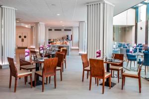 a dining room with tables and chairs and a restaurant at Barceló Corralejo Sands in Corralejo