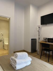 a room with a bed and a desk and towels at Thor Hostal Boutique in Alicante