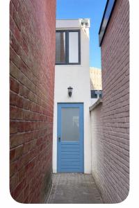 a blue door on a building with a brick wall at Zandvoort Beach Escape 2P in Zandvoort