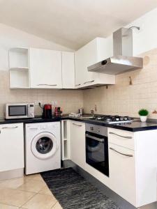 a kitchen with white cabinets and a washer and dryer at International House San Teodoro in San Teodoro