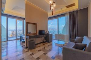 a living room with a couch and a desk with a television at Kronos Hotel in Golbası