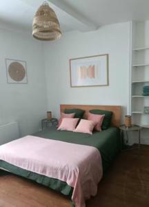 a bedroom with a bed with pink and green pillows at Le Nid De Demolombe in Caen