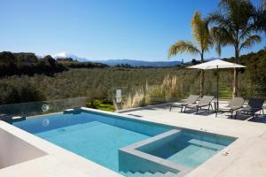 a swimming pool with chairs and an umbrella at Arbora Olea Luxury Villas in Skaleta