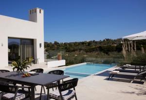 a patio with a table and chairs next to a swimming pool at Arbora Olea Luxury Villas in Skaleta