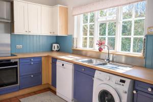 a kitchen with blue cabinets and a washer and dryer at 10 Pudding Bag Lane in Exton +9 photos