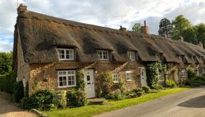 an old stone house with a thatched roof at 10 Pudding Bag Lane in Exton