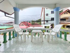 three white chairs and a table on a porch at Vacation Home Tambon Karon in Karon Beach