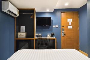 a room with a bed and a desk with a tv at Mybed Sathorn Hotel in Bangkok