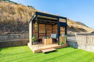 a wooden gazebo with a bench on a lawn at Casa Familia Aoshima in Miyazaki