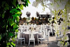 a wedding reception with white chairs and tables and flowers at Kronos Hotel in Golbası
