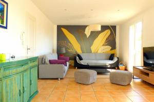 a living room with chairs and a couch and a tv at Spacious and bright house with swimming pool in Bandol