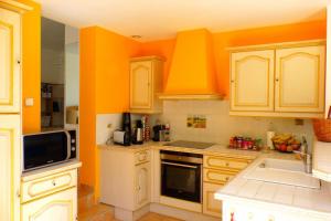 a kitchen with orange walls and white cabinets at Spacious and bright house with swimming pool in Bandol