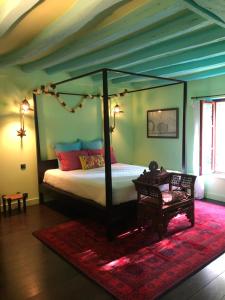 a bedroom with a canopy bed with a red rug at Domaine de l'Ocrerie in Pourrain