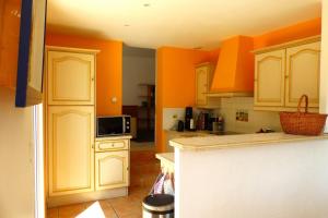a kitchen with orange walls and white cabinets at Spacious and bright house with swimming pool in Bandol