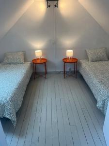 two twin beds in a room with two tables at La Renardière in Foreste