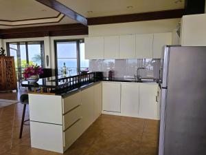 a kitchen with white cabinets and a stainless steel refrigerator at Baan Lom Talay Grand Villa Samui in Choeng Mon Beach