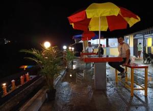 a man sitting at a table under an umbrella at Heritage Vagamon Cottages in Idukki +2 photos