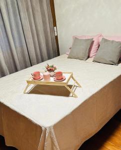 a bed with a tray with two cups on it at Chalé Garden - Pedra Azul in Domingos Martins
