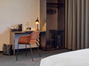a room with a desk and a chair next to a bed at B&B HOTEL Dresden City-Süd in Dresden