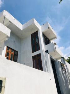 a white house with wooden doors andwindows at Ruk Mountain Hotel in Kengalla