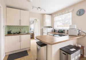 a kitchen with white cabinets and a counter top at Highview, extended 2 bedroom house, with view, near coast path in The Mumbles