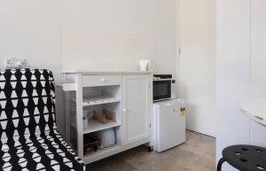 a small white kitchen with a microwave and a chair at Relax and Retreat Studio Flat in Glenwood