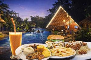a plate with a hamburger and french fries and a drink at Sigiriya River Side Resort in Sigiriya