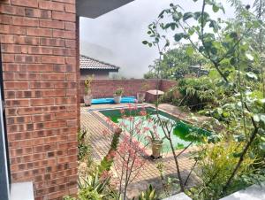 a garden with a swimming pool and a brick wall at Goodman's Guest home in Nelspruit