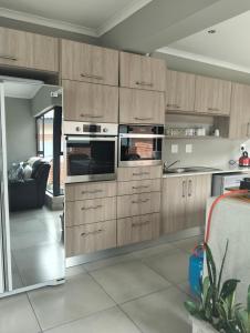 a kitchen with wooden cabinets and stainless steel appliances at Goodman's Guest home in Nelspruit