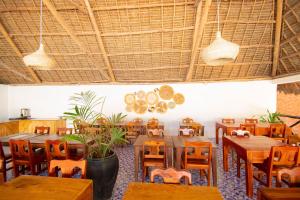 a dining room with wooden tables and chairs at Kigwedeni Villas in Nungwi