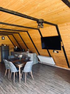 a room with a wooden ceiling with a table and a tv at Cabana Muncelus in Lupşa