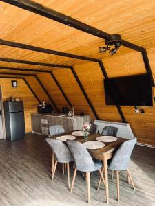 a dining room with a table and chairs and a tv at Cabana Muncelus in Lupşa