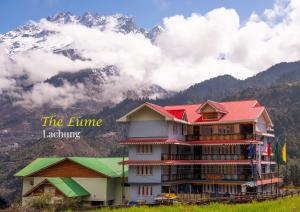 a building with a red roof in front of a mountain at The Lume, Lachung in Lachung