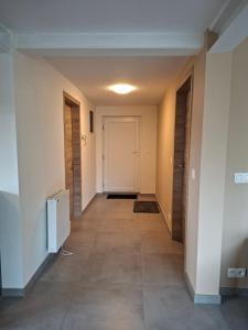 a hallway with white walls and tile floors and a door at Coolappart in Mont-Saint-Guibert