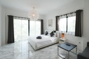 a white bedroom with a large bed and a chandelier at Z-Beach Resort in Ban Nong Ban Kao