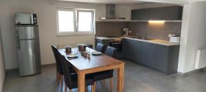a kitchen with a wooden table with chairs and a refrigerator at Coolappart in Mont-Saint-Guibert