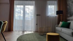 a living room with a couch and two large windows at LEO Apartman in Veszprém